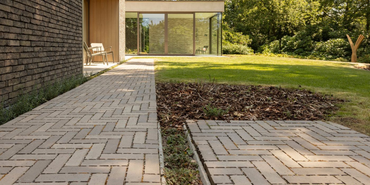 Modern property with herringbone paved path around the sides