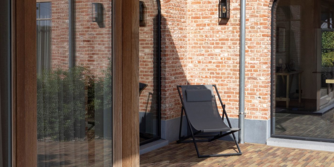 Paved area outside double doors with a garden chair in the corner