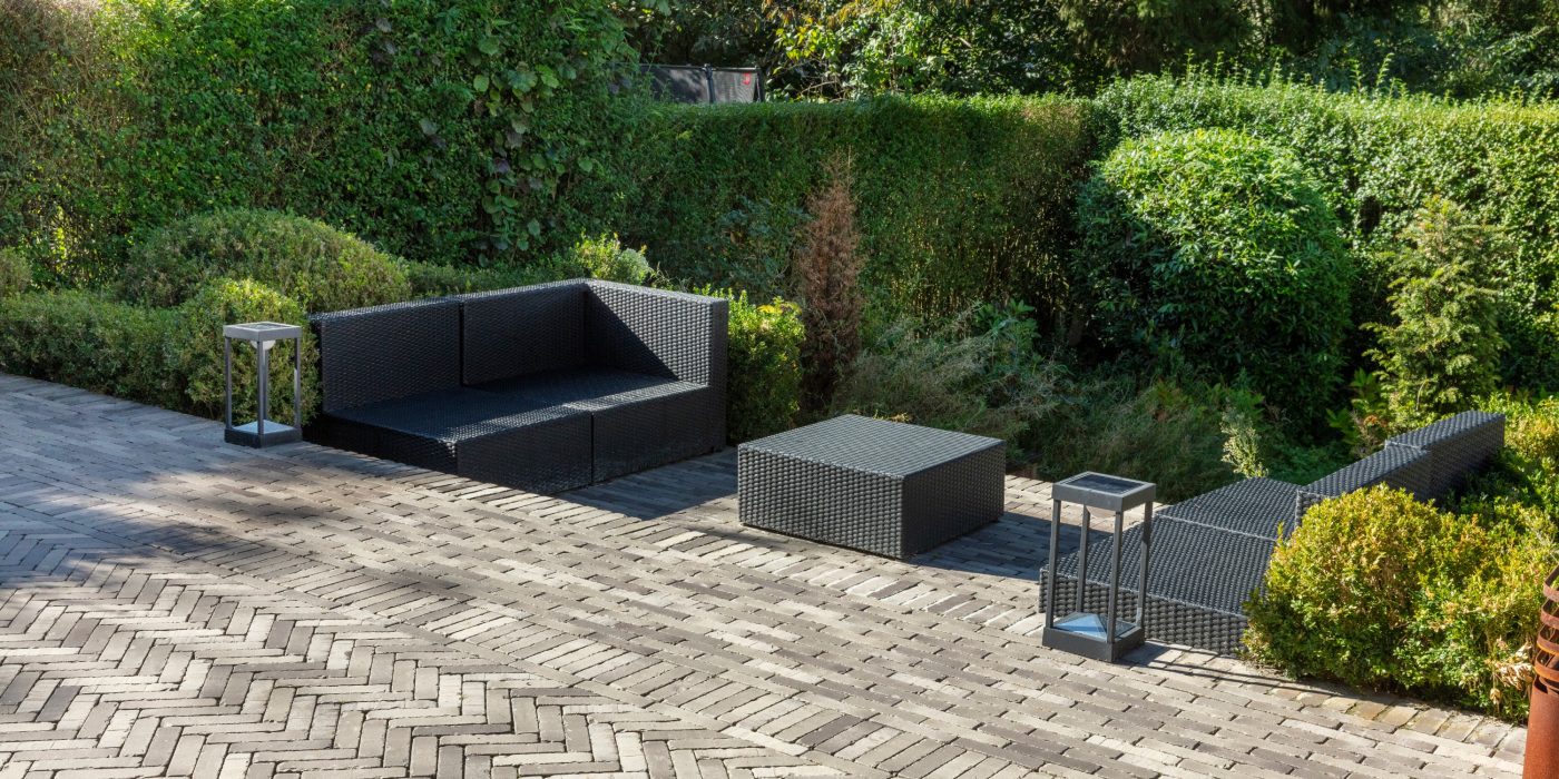 paved patio with garden furniture out surrounded by bushes