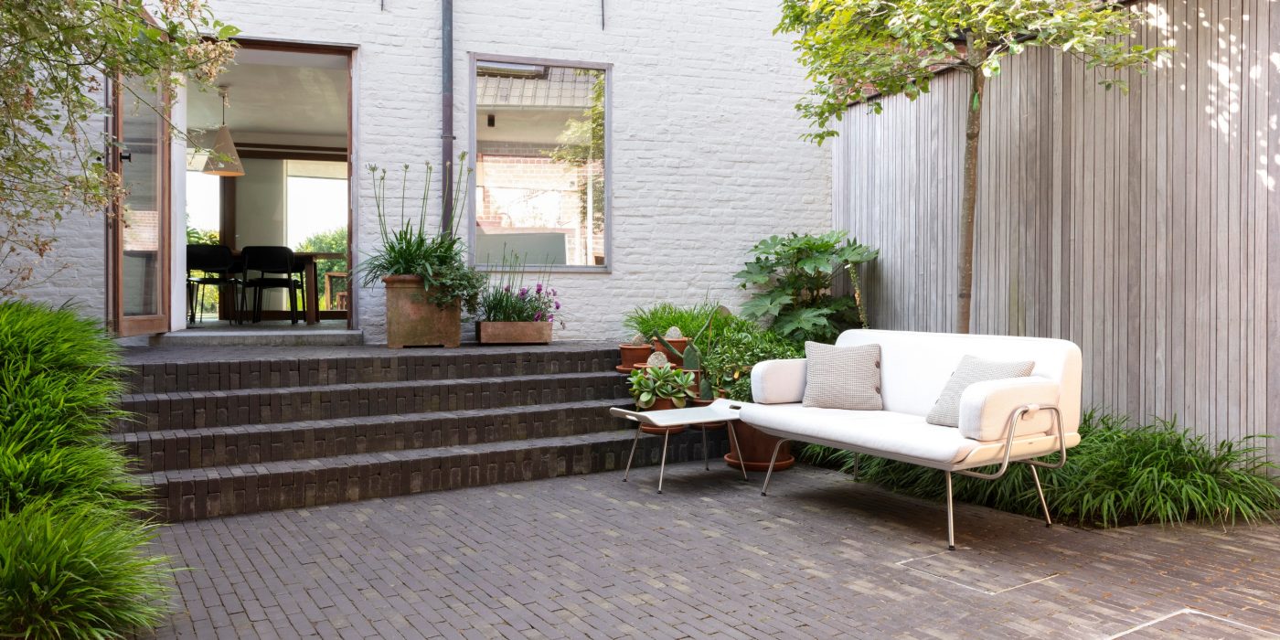 Paved outdoor courtyard with plants, steps and white outdoor seating