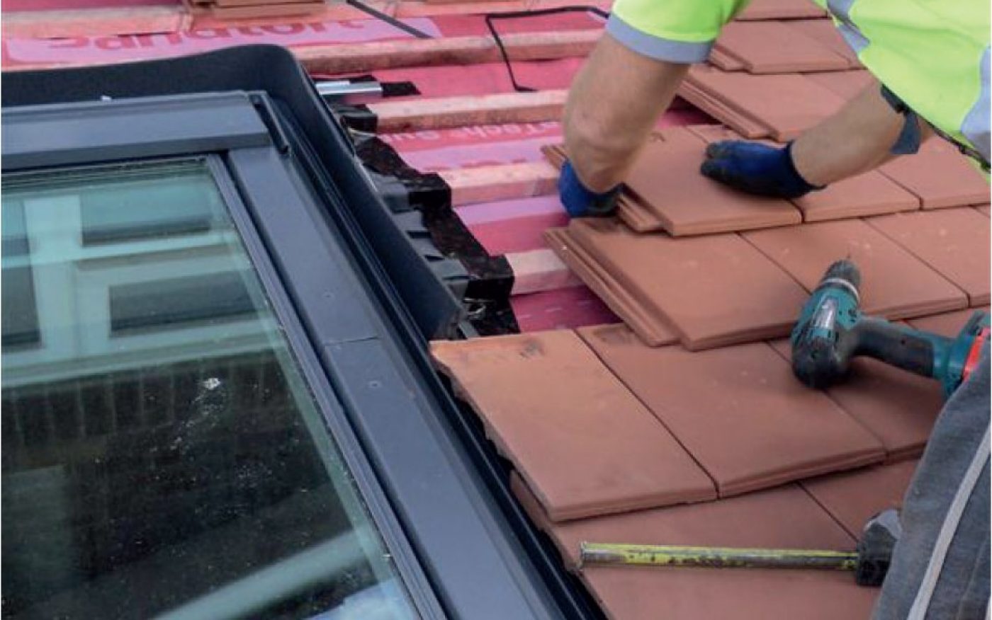 Man installing the roof tiles round a window