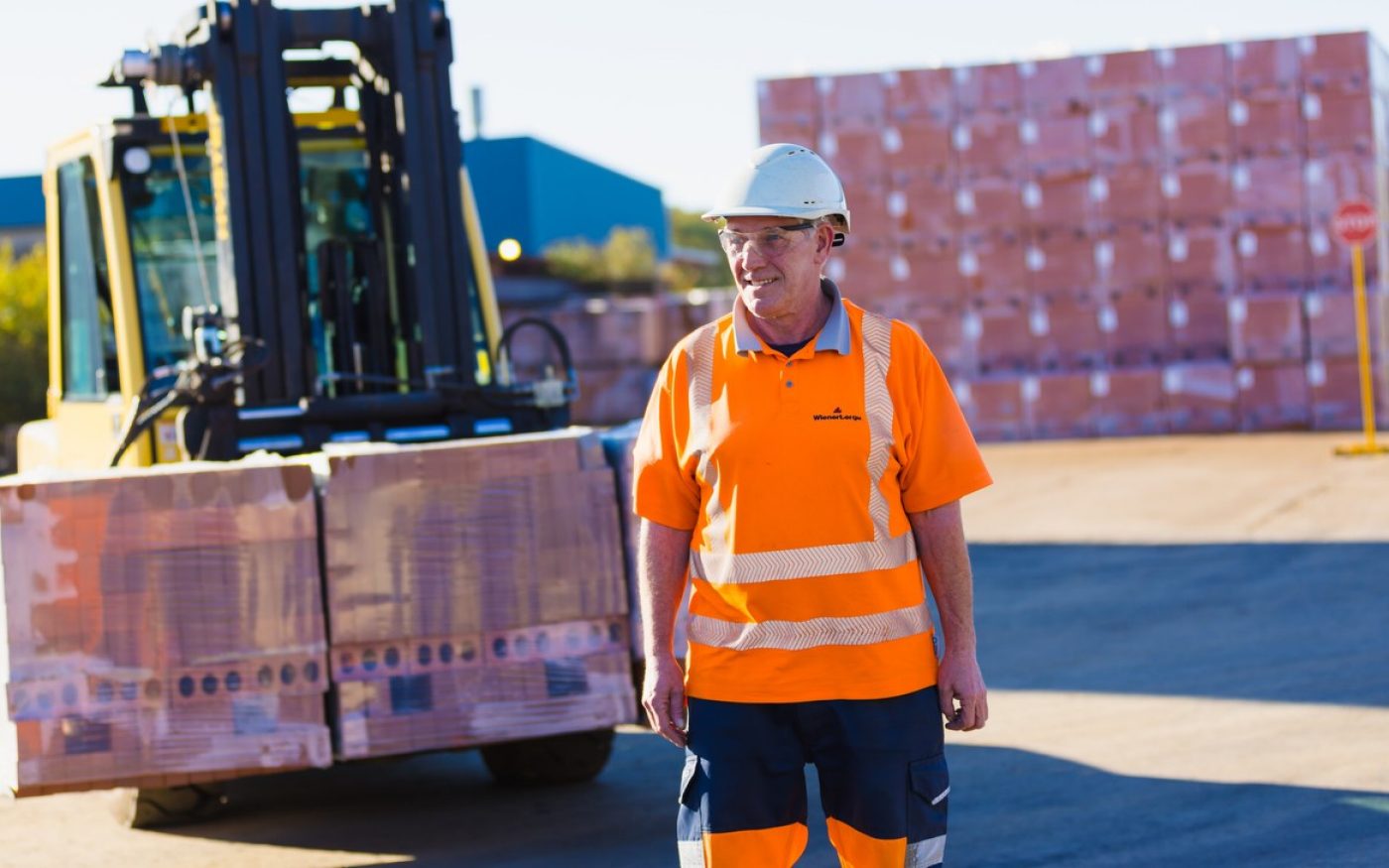 Man in safety gear in front of forklift truck with bricks